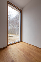 Close-up of wide window views the forest of the Swiss Alps. Copy space