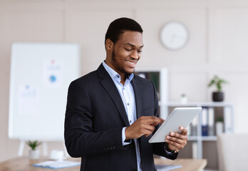 Obraz na płótnie Canvas Smiling black manager using digital tablet, office interior