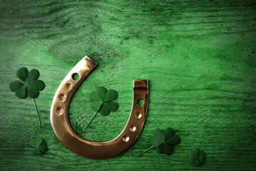 Clover leaves and horseshoe on green wooden table, flat lay. St. Patrick's Day celebration