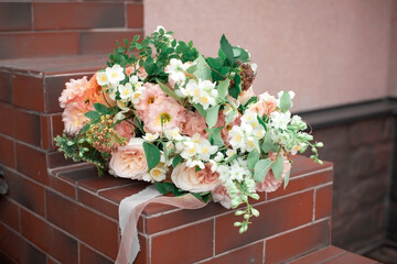 Orange and green wedding bouquet on the red stone steps
