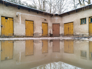 Small building with few doors reflected in small puddle