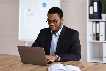 Young black entrepreneur working with laptop, office interior