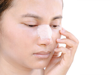 portrait of beautiful young female face with bandage on her nose - beauty treatment plastic surgery isolated on gray background