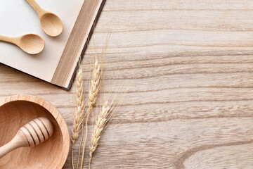 Fototapeta na wymiar Top view wooden table, Create style table kitchen with wooden spoons, blank book, ear of rice, wooden honey stick and wood bowl is elements with copy space.