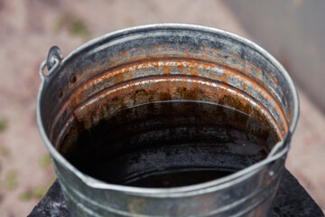 Abandoned rusty metal water bucket.