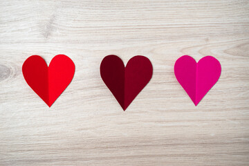 Fototapeta na wymiar Cutted and folded paper Red hearts on a bright wooden Background. Card for Valentine's Day.