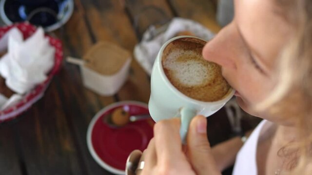 Top view of female drinking cappuccino coffee. Pastries served on wooden table