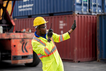 Worker man in protective safety jumpsuit uniform with yellow hardhat and use  Walkie Talkie check container at cargo shipping warehouse. transportation import,export logistic industrial service