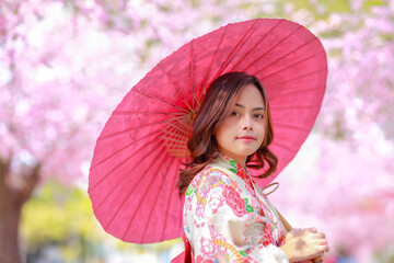 Portrait of a traveler young asian woman wear a dress yukata and walking on tree path in japan...