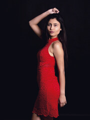 Sexy woman wearing red lace dress . Portrait shoot in the studio . Black background