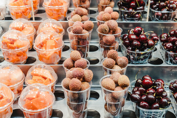 Fruit Salad arranged in plastic cups on a market stall with small fork inside, takeaway snack