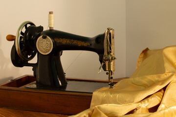 gray sewing machine on a white background with golden fabric