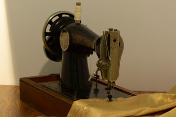 gray sewing machine on a white background with golden fabric