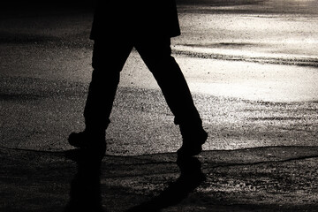Black silhouette and shadow of person walking down on a street. Concept of loneliness, hurrying...
