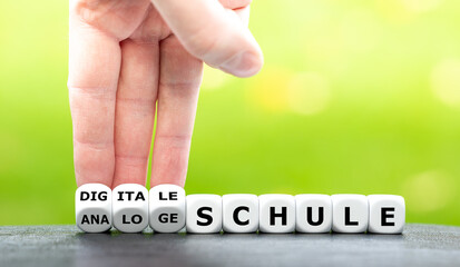 Hand dreht Würfel und ändert den Ausdruck "analoge Schule" in "digitale Schule".