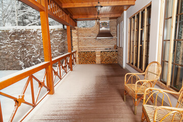 Two wicker chairs stand on veranda on winter day