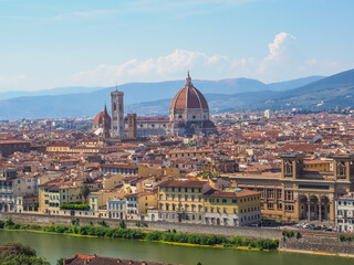 Fototapeta na wymiar Beautiful cityscape of Florence. Famous Cathedral of Santa Maria del Fiore with red-tiled dome, marble facade and elegant Giotto Bell Tower in the center, National Library on the left side, Arno river