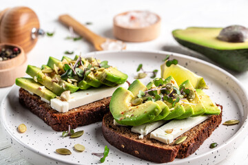 healthy toasts with avocado cheese and whole wheat rye bread on a plate. Delicious snacks and avocado sandwiches. Vegetarian food. Vegan menu. Food recipe background