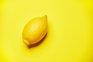 Single fresh raw clean yellow whole one alone diagonally oriented ripe lemon isolated on the bright...