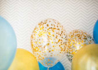 Blue and transparent balloons with golden confetti on zigzag wallpaper background