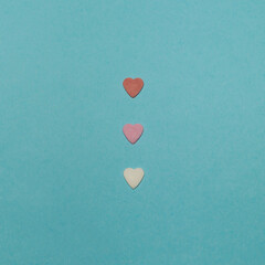 Fototapeta premium Three hearts in a row on blue background. Minimalistic composition.