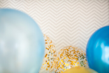 Blue and transparent balloons with golden confetti on zigzag wallpaper background