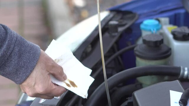 Inserting a dipstick to check the oil in a car