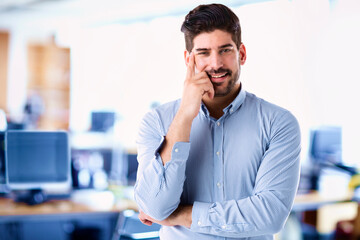 Happy businessman standing in the office while looking at camera and smiling