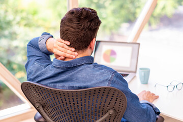 Unrecognizable businessman sitting at office desk and has a pain in his nape