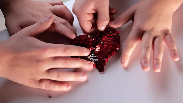 boy and girl hands touches heart with red sequins. Love. Valentine's Day romantic decoration composition. Slow motion