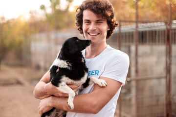 Smiling kind man with dog in animal shelter - obrazy, fototapety, plakaty