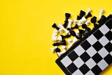 Chess board and chess figures on yellow background. Flat lay, copy space. Black and white chess...