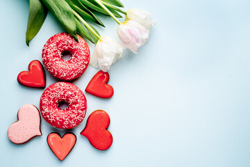 International Women's Day. 8 march number eight consisting of donuts next to tulips and heart-shaped cookies on a light blue background with copy space for your text