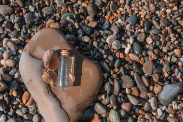 A flat lay of glass bottle with sea water and clam shells are on a wet stone.  Sea coast hydrotherapy concept.