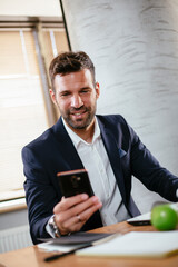 Businessman typing a message. Company manager on his phone sending a message.