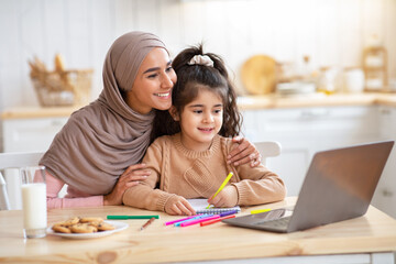 Loving Muslim Mom Helping Her Little Daughter Study With Laptop At Home