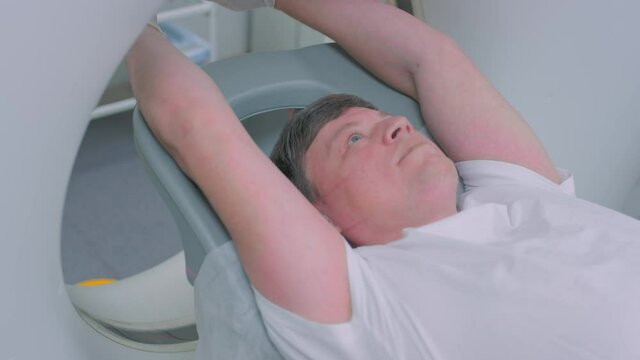 A patient in a protective medical mask lies in a modern computed tomography apparatus. The doctor analyzes the lungs on a CT scanner. The danger of covid or coronavirus. Human lung scans