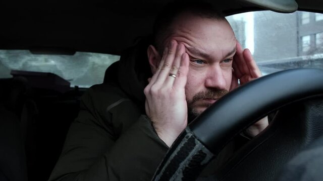 The driver rubs his head. Fatigue, lack of energy while driving.
