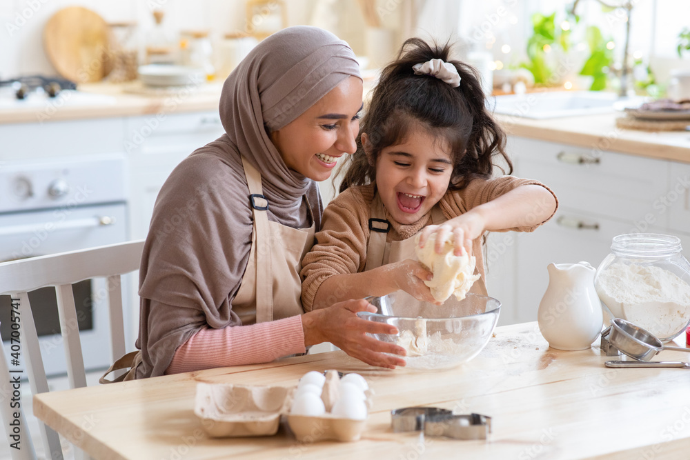 Wall mural Muslim Mom And Daughter Having Fun At Home, Baking In Kitchen Together