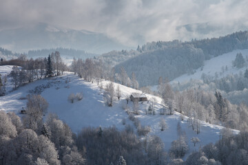 Naklejka premium Winter frosty landscape of the beautiful Transylvanian village, Bran, with fresh snow, at the foot of the Carpathian Mountains