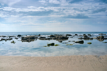 Fototapeta na wymiar Sand and rock beach against the blue sky with stratocumulus clouds on Tarifa coast. Natural seascape