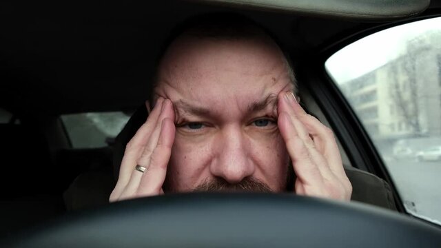 The driver rubs his head. Fatigue, lack of energy while driving.