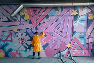 Crédence de cuisine en verre imprimé Graffiti Artiste de rue peignant des graffitis colorés sur le mur