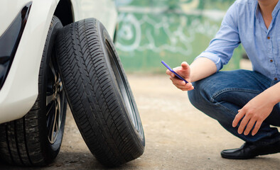 Man holding a call to take pictures Auto spare tires to prepare for repairs Or change by yourself, the idea of ​​changing tires when entering the rainy season and winter
