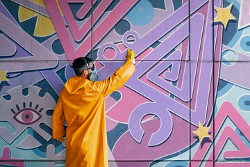Street artist painting colorful graffiti on wall