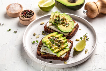 avocado toasts with rye bread, sliced avocado, pumpkin and sesame seeds, salt and pepper. Vegetarian sandwiches delicious breakfast or snack