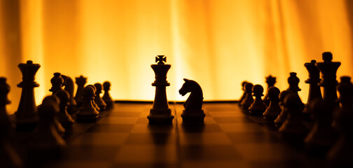 silhouette of King versus horses chess board game on cold color tone background