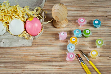 Multicolored paints and Easter eggs on a wooden table. Sets for coloring Easter eggs. Top view. Copy space and place for text near paints.