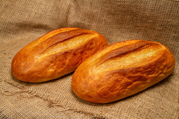 Two loaves of fresh white bread on a background of black bread.