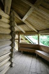 An old wooden veranda in the old Russian style. Carved benches for seating are located along the windows.